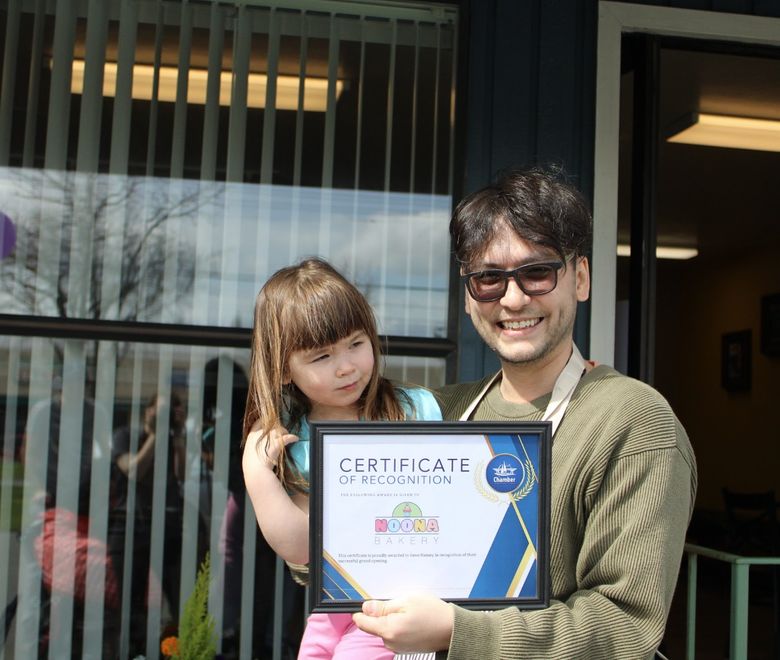 Noona bakery owner holding sign
